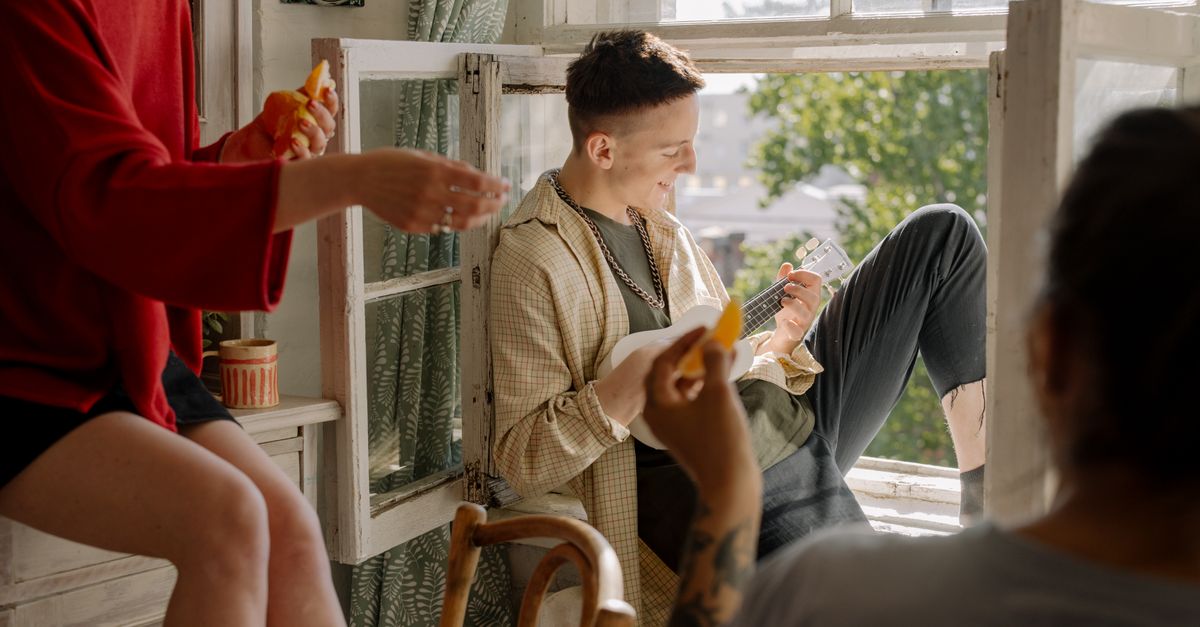 A group of friends sitting around a table with laptops and smartphones, reviewing shared expenses on a screen.