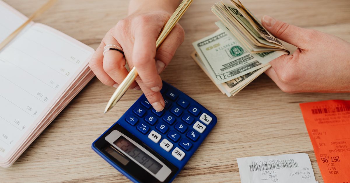A person using a smartphone to review shared expense balances in a bright room.